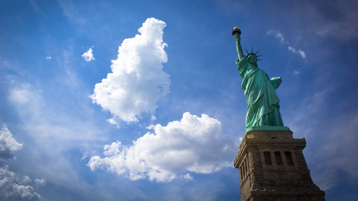Statue of Liberty against a blue sky with clouds