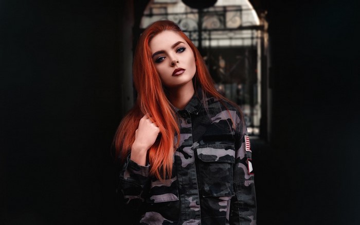 Redhead woman in camouflage jacket posing