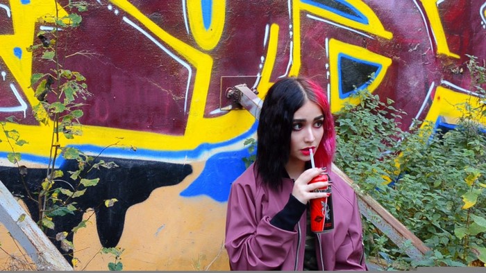 Woman with pink and black hair drinking from a can