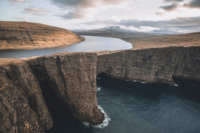 Cliff overlooking a lake and ocean in the Faroe Islands