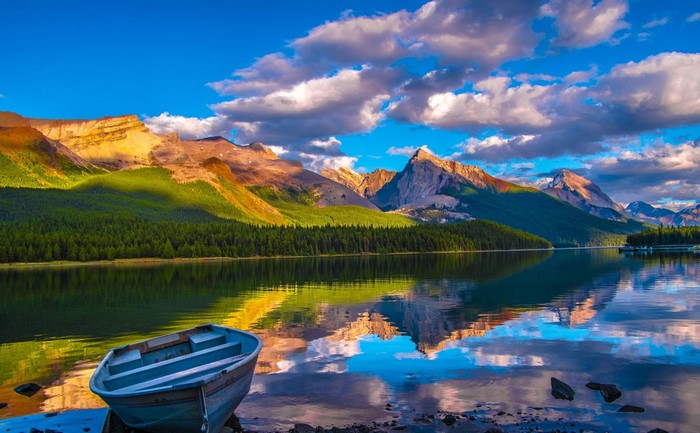 Boat on a lake with mountains and forest reflection