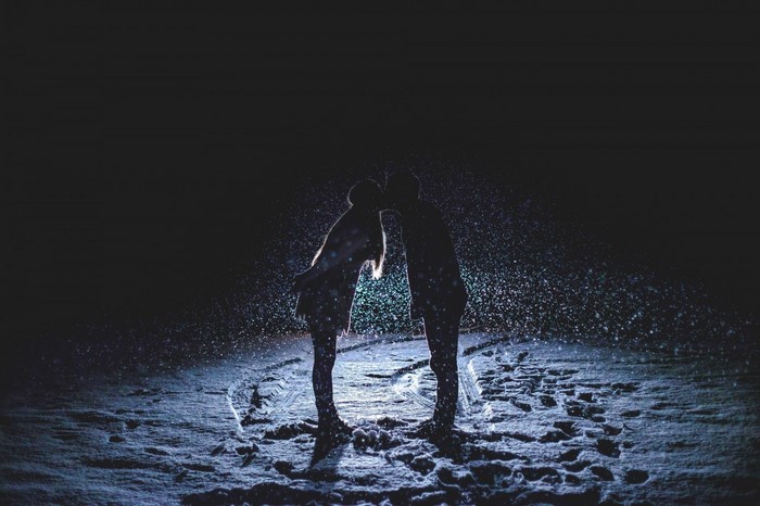 Couple kissing in the snow at night