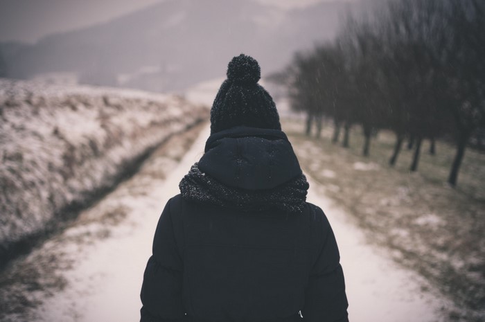 Person in winter coat walking on snowy path