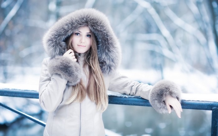 Woman in fur-lined winter coat in snowy forest