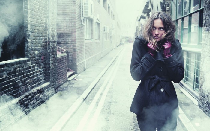 Woman in black coat and pink gloves in alley