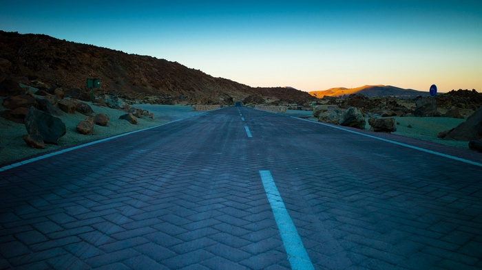 Road through a rocky, mountainous landscape at sunset