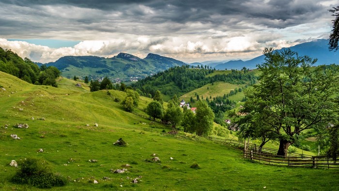 Lush Green Hills and Mountain Ridge under Cloudy Sky