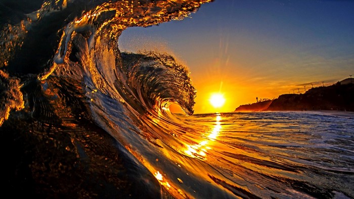 Ocean wave crashing at sunset with golden light