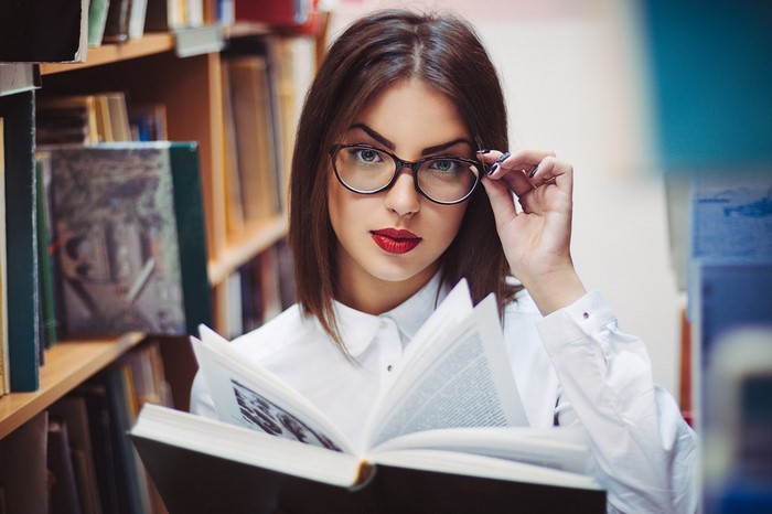 Woman with glasses reading a book in a library