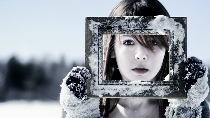 Girl holding a snow-covered picture frame in winter