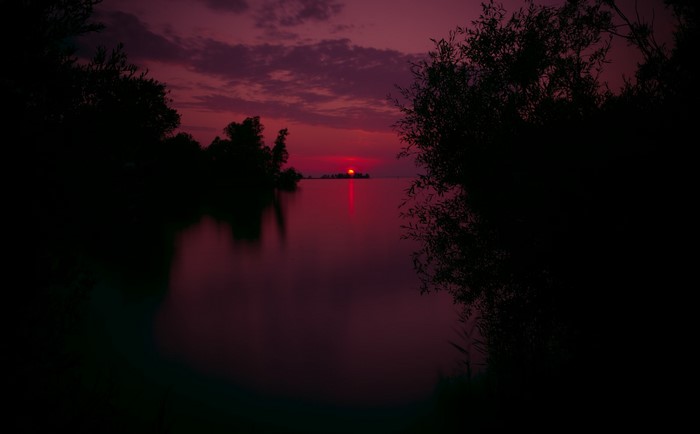 Sunset over a calm lake with silhouetted trees