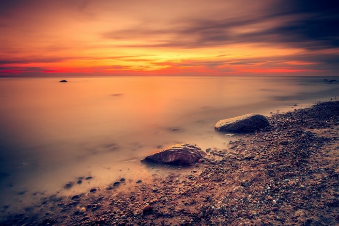 Sunset over the sea with rocks on the beach