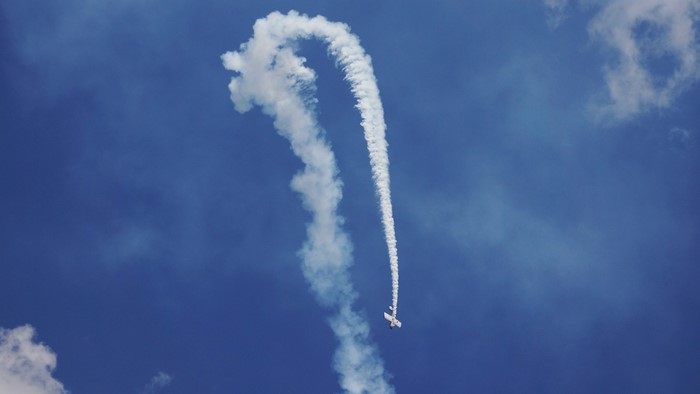 Airplane performing stunts in a blue sky with clouds