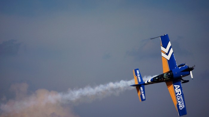 Blue and orange National Guard aerobatic airplane performing stunts
