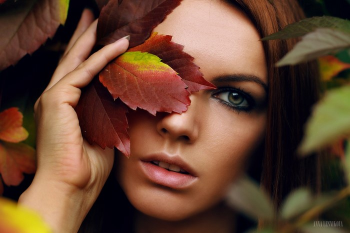 Woman with autumn leaves covering her eye