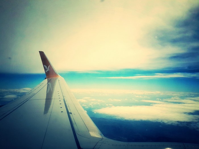 Airplane wing flying above clouds during sunrise