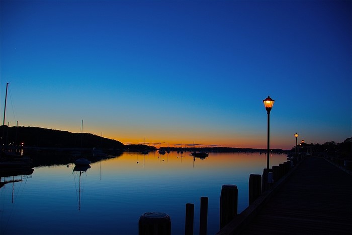 Sunset over a harbor with boats and a pier