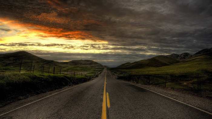 Road through rolling hills at sunset