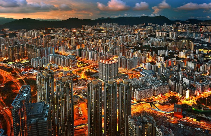 Aerial view of a sprawling city at dusk with illuminated skyscrapers and traffic