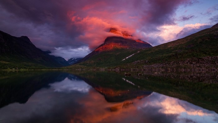 Mountain lake at sunset with colorful clouds and reflection