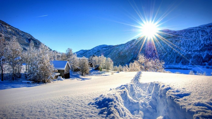 Snowy landscape with mountains and a bright sun