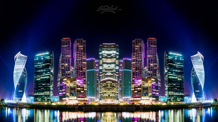 Cityscape with illuminated skyscrapers at night reflected in water