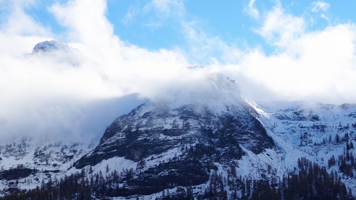 Snow-covered mountains with clouds and trees