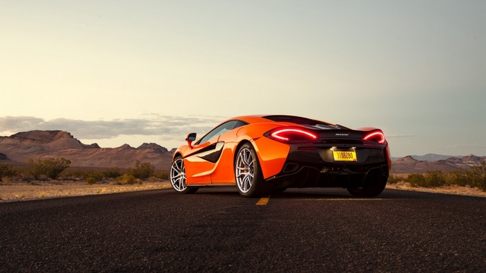 Orange McLaren 570S sports car on a desert road