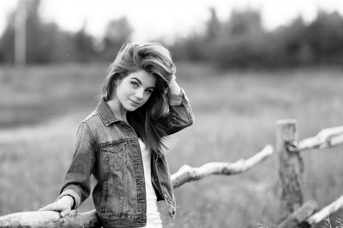Monochrome portrait of a young woman in a denim jacket outdoors