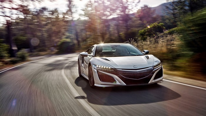 White Honda NSX sports car driving on a winding road