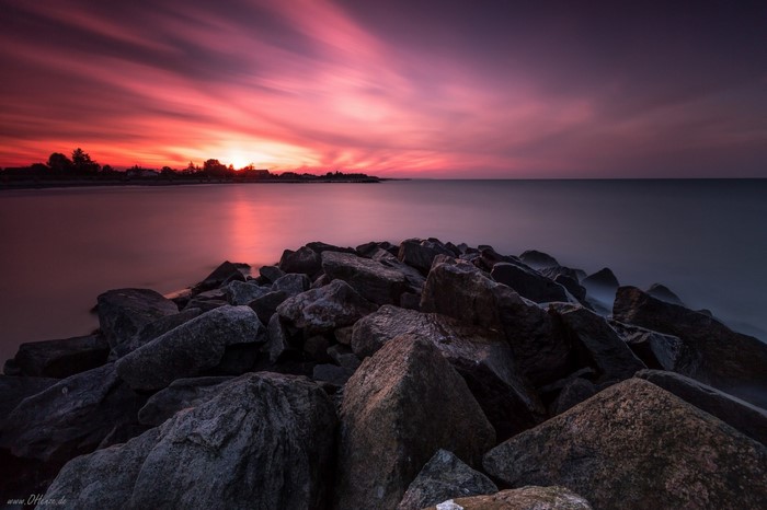 Sunset over the ocean with rocks in the foreground