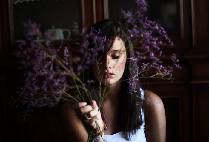 Woman holding purple flowers in front of her face