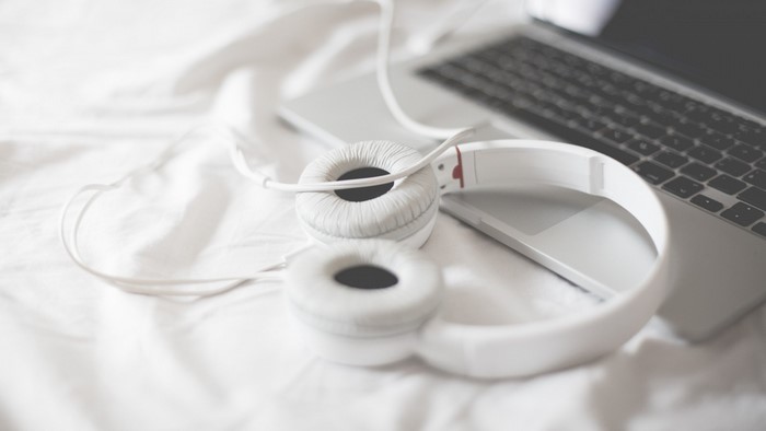 White headphones and MacBook on white sheets