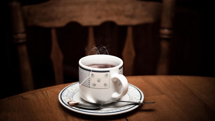 Steaming cup of tea on a saucer with a spoon