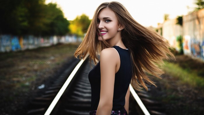 Woman with long brown hair on train tracks
