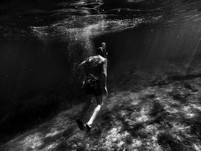 Man snorkeling underwater in dark water