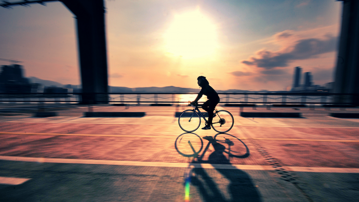 Silhouette of a cyclist on a bridge at sunset