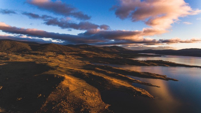 Sunset over a vast landscape with mountains and a lake