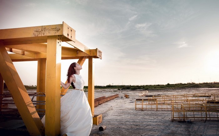 Woman in white dress standing near yellow structure outdoors