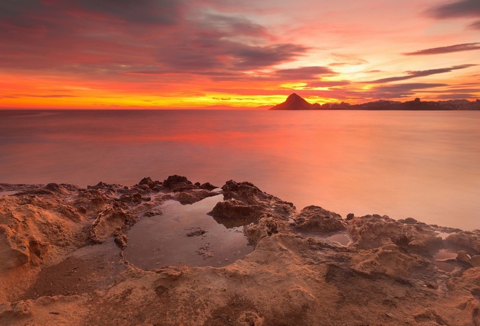 Sunset over the sea with rocky shore