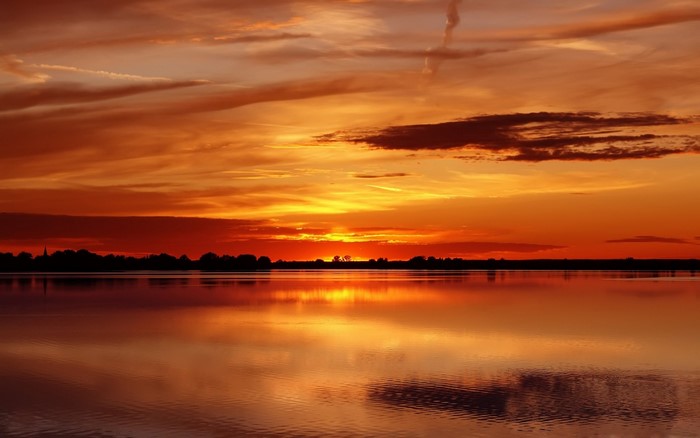Sunset over a calm lake with silhouetted trees