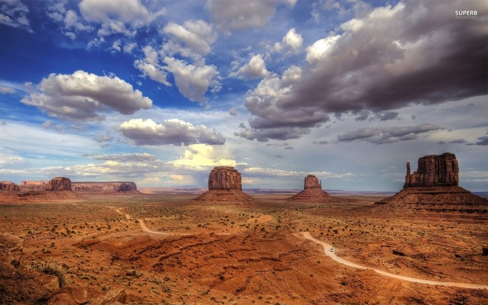 Monument Valley landscape with buttes and road under cloudy sky