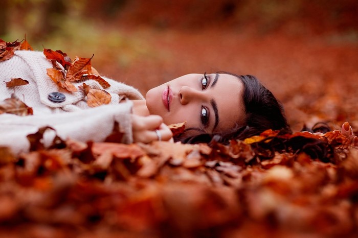 Woman lying in autumn leaves