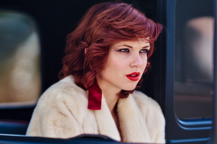 Woman with red hair and fur coat in a car