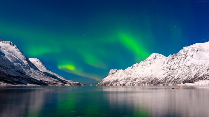 Aurora Borealis over snow-covered mountains and lake