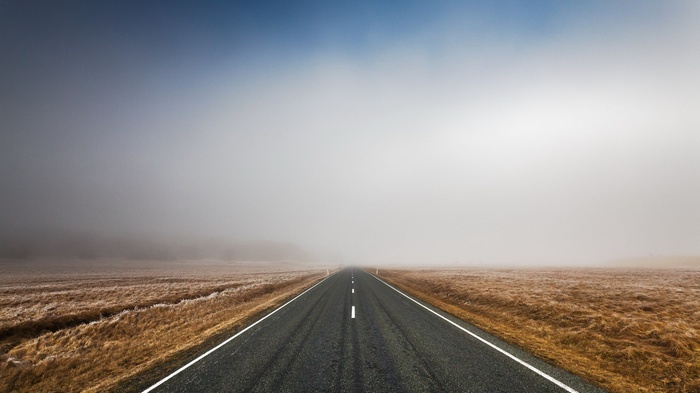 Empty road disappearing into fog