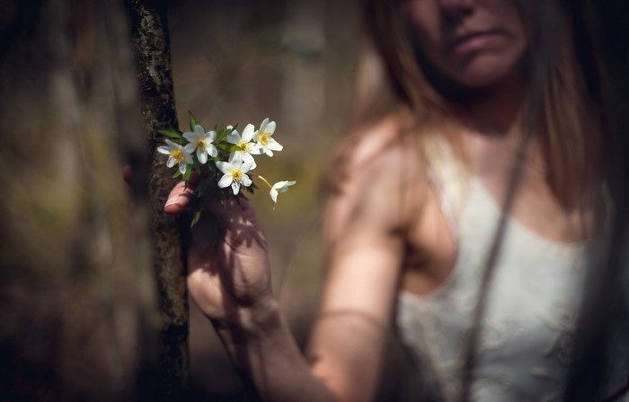 Woman holding white flowers near a tree