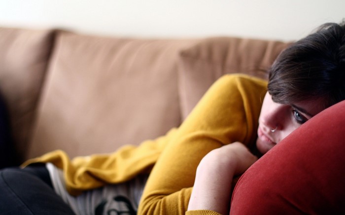 Woman lying on a couch with a red pillow