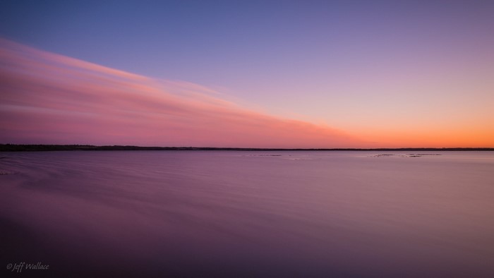 Sunset over a calm body of water with pink clouds