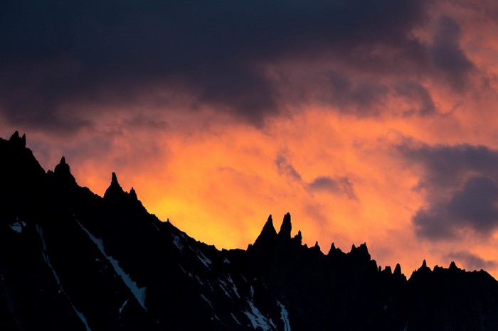 Silhouette of jagged mountains against a fiery sunset sky
